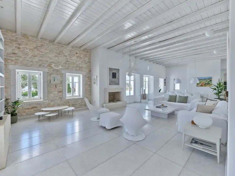 Main living room with natural-stone wall and white-beamed ceiling