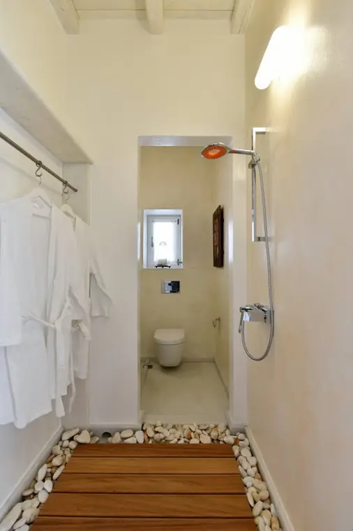 Walk-in shower suite with natural pebbles and wood floor